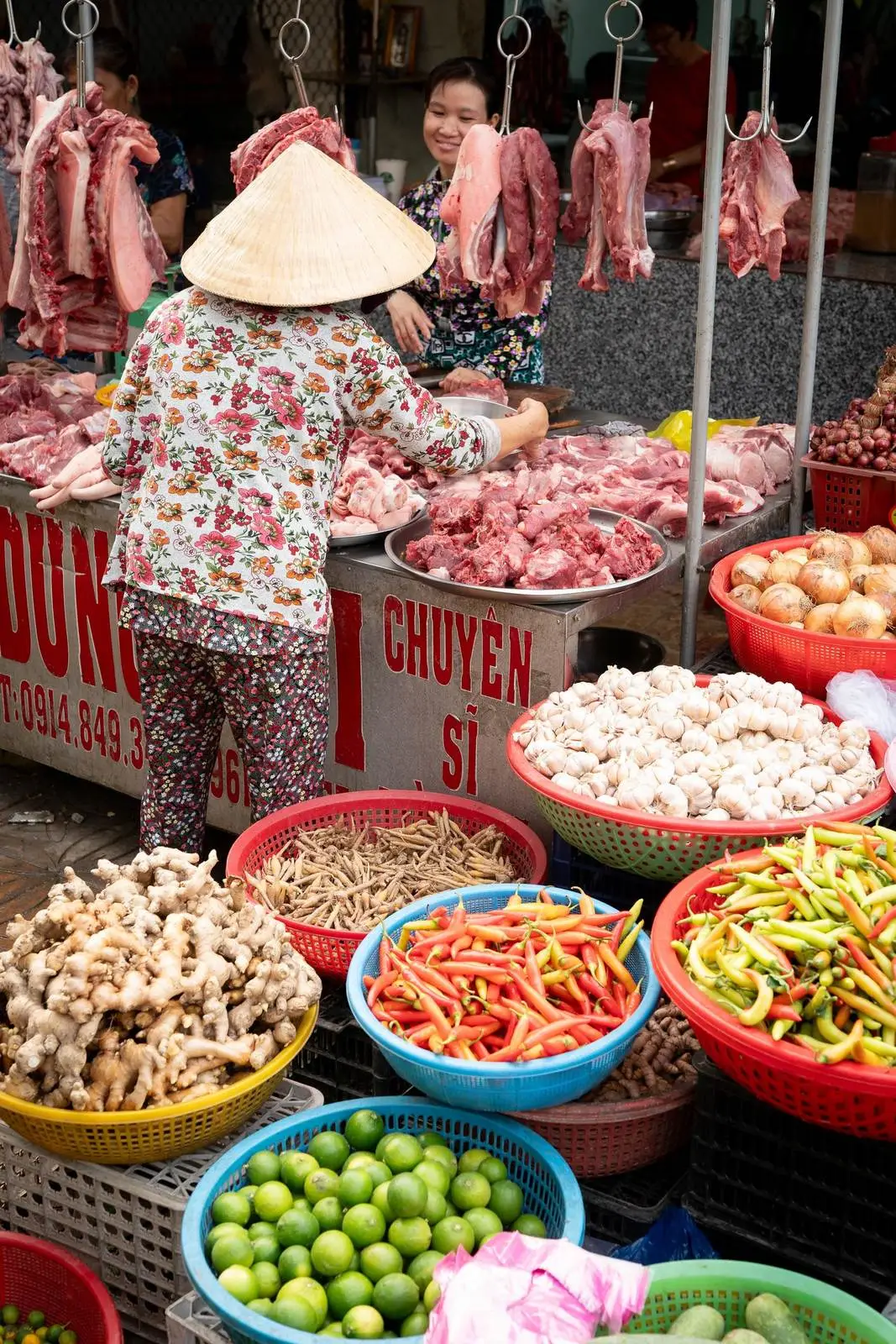 Продавщица в конической шляпе нон ла выбирает мясо на рынке Дананга